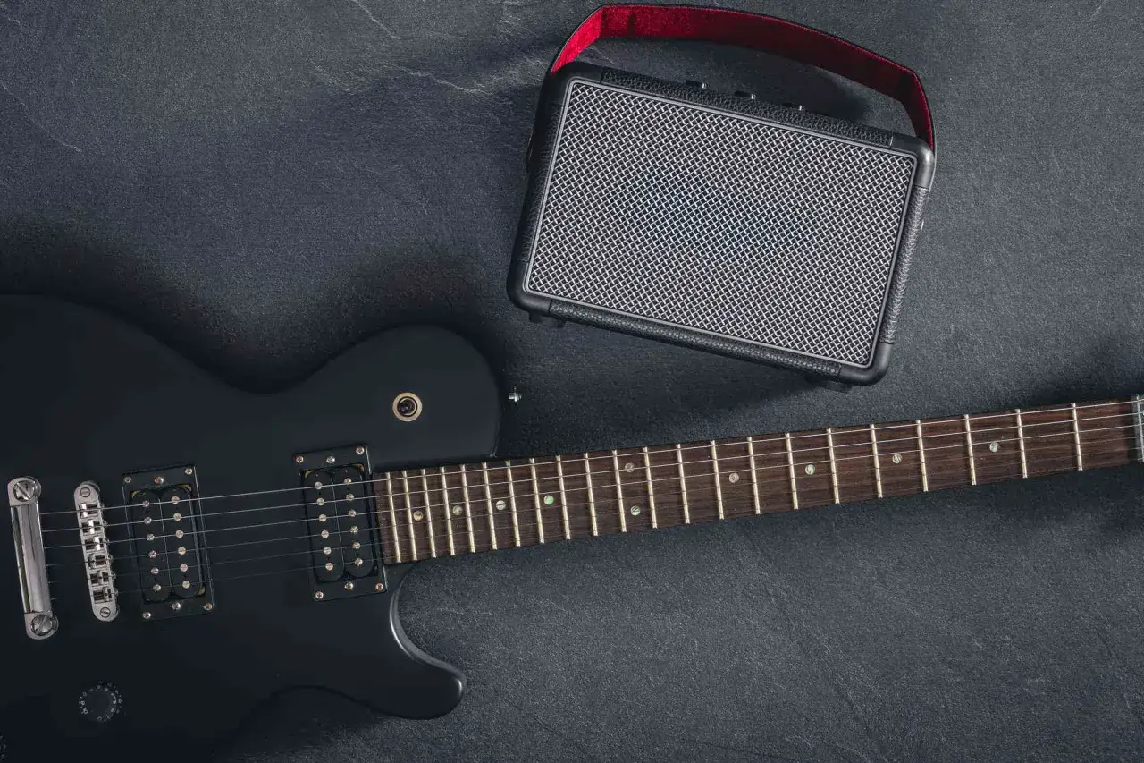 Czarna gitara elektryczna i mały wzmacniacz. Idealny zestaw, by zacząć przygodę, jak zrobić gitarę elektryczną.