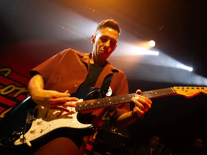 Cory Wong w akcie tworzenia muzyki na scenie, skupiony na grze na gitarze elektrycznej.